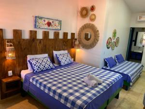 a bedroom with two beds with blue and white pillows at Maria Flor Pousada in Taíba