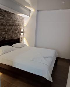 a bedroom with a white bed and a brick wall at Santorini colombiano en Doradal in Puerto Triunfo