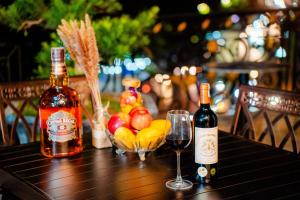 two bottles of wine and glasses on a table with fruit at Victory Hotel in Hanoi