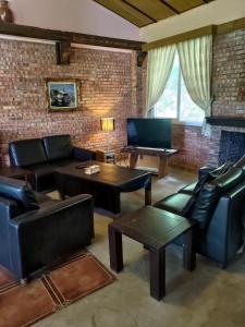 a living room with leather furniture and a brick wall at 愛上龍過脈民宿 in Ch'u-lu