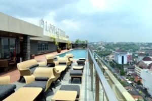 a balcony with chairs and a swimming pool on a building at Channel Stay Warhol Simpang Lima Semarang in Semarang