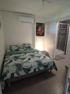 una camera con un letto e un piumone verde e bianco di Appartement Clos du bois a Fort-de-France