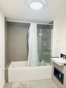 a bathroom with a tub with a shower and a sink at Courtyard tranquil lodge in London