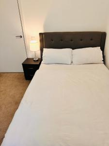 a bedroom with a large white bed with a lamp at Courtyard tranquil lodge in London