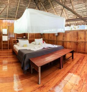 Cama en habitación con suelo de madera en Ecolucerna Lodge Tambopata, en Puerto Maldonado