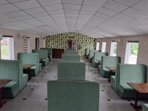 GREEN VALLEY SARISKA في Tehla: غرفة قطار فارغة مع كراسي وطاولات خضراء