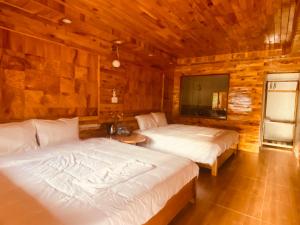 a bedroom with two beds in a wooden cabin at Sun Hill's House in Cham Ta Lao