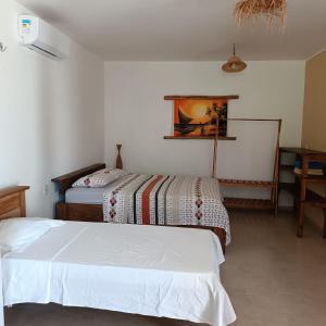 ein Schlafzimmer mit zwei Betten und einem Tisch in der Unterkunft Chalé Calú in Barra Grande