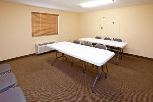 Candlewood Suites Lafayette, an IHG Hotel في لافاييت: قاعة اجتماعات مع طاولات وكراسي بيضاء