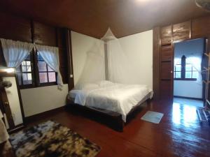een slaapkamer met een wit bed en een houten vloer bij เฮือนฮิมธารโฮมสเตย์ in Ban Pang Champi