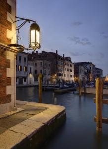 a light hanging from a building next to a river at Hotel L'Orologio - WTB Hotels in Venice