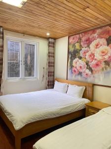 a bedroom with two beds and a painting on the wall at ROSE MOTEL in Sa Pa