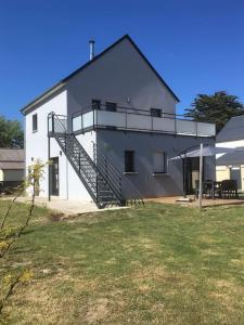 a large white building with a staircase next to a yard at MAISON DE VACANCES 4 Clés - BORD DE MER DENNEVILLE PLAGE in Denneville