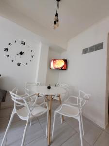 a dining room with a table and chairs and a clock at Departamentos Ines 1 in Junín