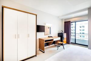ein Zimmer mit einem Schreibtisch und einem großen Spiegel in der Unterkunft Aliz Hotel in Nonthaburi