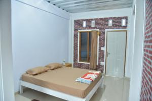 Dormitorio pequeño con cama y pared de ladrillo en Toraja Dannari Homestay, en Rantepao