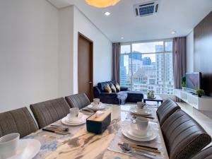 Soho suites klcc by Homestay في كوالالمبور: غرفة معيشة مع طاولة مع كراسي وأريكة