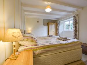 um quarto com uma cama e uma mesa com um candeeiro em 1 Gabberwell Cottages em Kingston