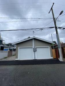 a house with two white garage doors on a street at New Modern Theee-room Duplex-2791 in Vancouver