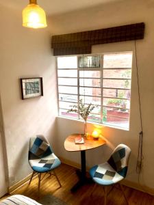 een kamer met een tafel, 2 stoelen en een raam bij Indigo Guest House in Mexico-Stad