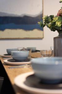 a table with bowls and a vase with flowers on it at #55highstreetauckland in Auckland