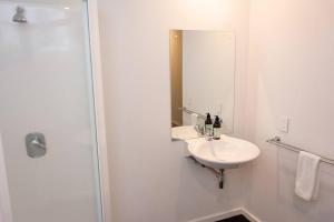 a white bathroom with a sink and a mirror at #55highstreetauckland in Auckland