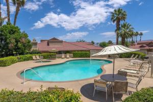a swimming pool with a table and chairs and an umbrella at Woodhaven Incredible Views on the Golf Course in Palm Desert