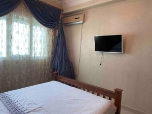 1 dormitorio con 1 cama y TV en la pared en Appartement de standing calme en centre ville IMAZUR en Tánger