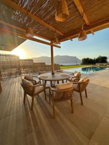 a patio with a table and chairs and a pool at Nusa Retreat - Seaview luxury residences - ideal for groups in Kissamos