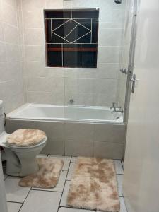 łazienka z wanną, toaletą i oknem w obiekcie Home away from Home w mieście East London