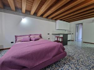 a large purple bed in a room with a kitchen at Appartamento con terrazzo in Udine