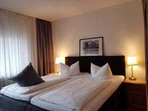 ein Schlafzimmer mit einem großen Bett mit weißer Bettwäsche und Kissen in der Unterkunft Apart Hotel Freiburg in Freiburg im Breisgau