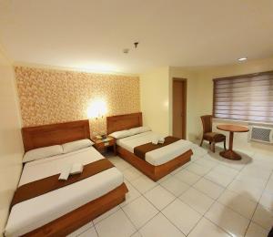 Rosas Garden Hotel في مانيلا: غرفة فندقية بسريرين وطاولة