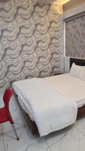 a bedroom with a bed and a red chair at Hotel holiday residency in Sāgwāra