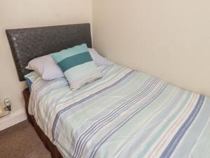 1 cama con manta de rayas azul y blanco en Ty Potiwr, en Conwy
