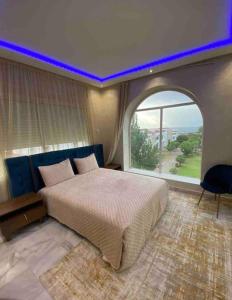 luxury condo with sea view في طنجة: غرفة نوم مع سرير كبير مع نافذة مقوسة