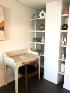 a desk and a chair in a room with shelves at Stylish Central Lake View Apartment in Canberra