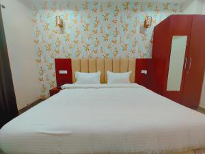 Awadh Samrat Resort في Ayodhya: غرفة نوم مع سرير أبيض كبير مع ورق جدران زجاجي