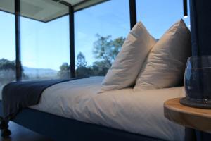 Una cama con sábanas y almohadas blancas y una mesa. en Avion Retreat en Pumpenbill