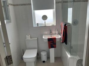 a white bathroom with a toilet and a sink at Beautiful Seafront Studio Apartment in Cleethorpes