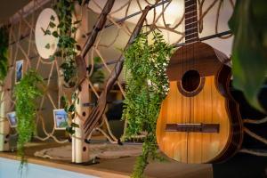 eine hölzerne Gitarre, die mit Pflanzen an einer Wand hängt in der Unterkunft Cabane pour vos vacances à 190m du lac d’Annecy in Menthon-Saint-Bernard