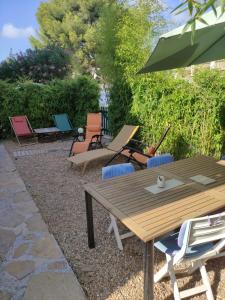 um pátio com uma mesa e cadeiras de madeira e um guarda-sol em La Bastide, 100m des rues piétonnes, jardin em Sanary-sur-Mer