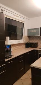 a kitchen with black cabinets and a microwave and a window at Kaja Apartament 52m2 in Pruszcz Gdański