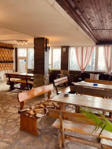 Хижа Тополица -The beautiful view في Aytos: غرفة بها طاولات خشبية ومقاعد ونوافذ