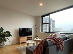 a living room with a couch and a large window at Brand new 1BR apartment Dickson in Canberra