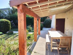 uma pérgola de madeira com uma mesa e cadeiras num pátio em chambre d'hôte dans maison privée em Périgueux