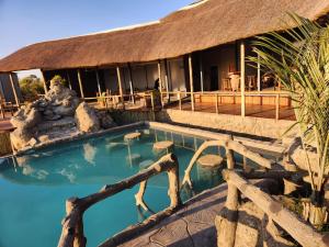 a resort with a swimming pool in front of a building at Mababe River Lodge in Mababe