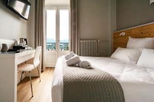 um quarto de hotel com uma cama, uma secretária e uma janela em Hôtel Gallia em Aix-les-Bains