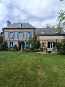 een groot bakstenen huis met blauwe ramen en een tuin bij La mare aux petits diables in Équemauville