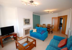 a living room with a blue couch and a tv at Alojamento Turistico in Maceira